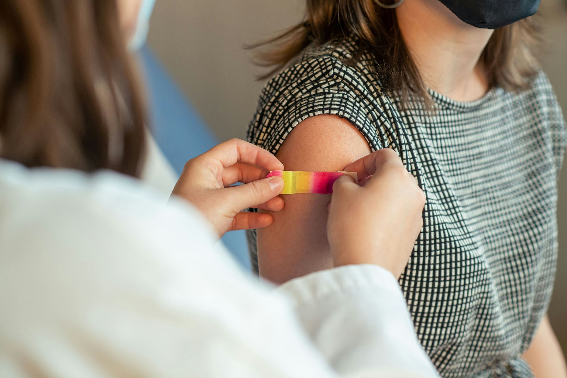 a plaster being applied to patient upper arm after vaccination